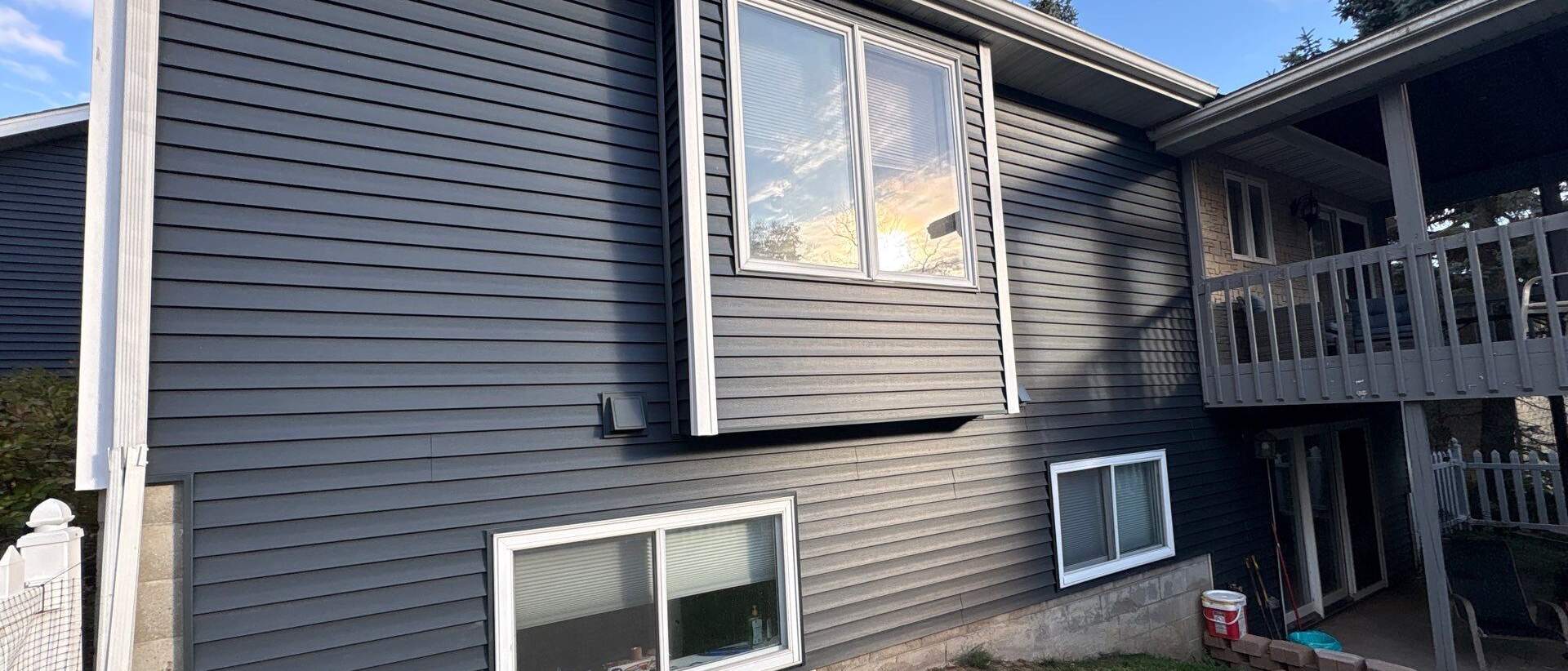 Gray vinyl siding on a two-story home with a back deck