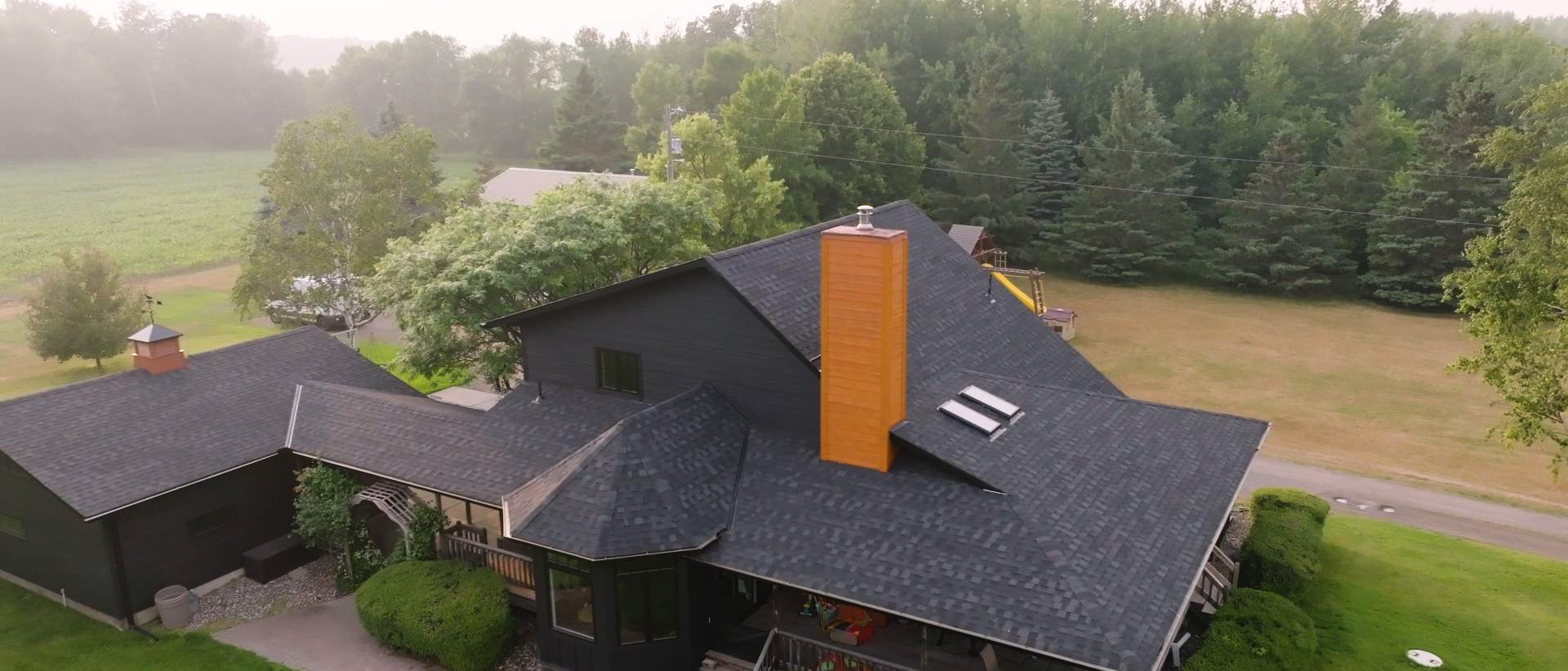 A contractor installing asphalt shingles and replacing siding on a residential roof. | Omega Exteriors