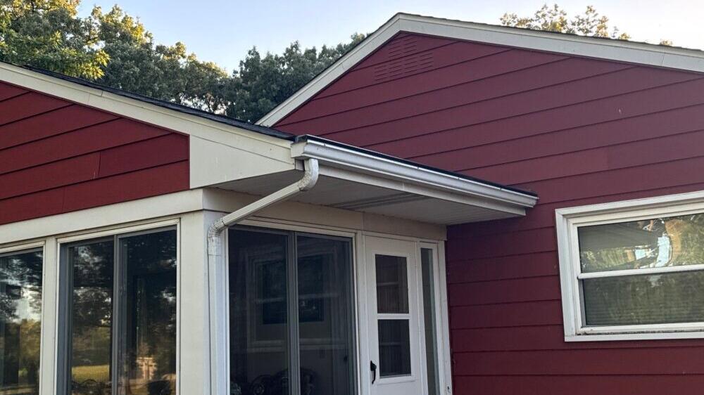 White gutters and downspout on a red-sided home