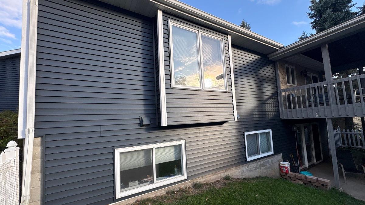 Gray vinyl siding on a two-story home with a back deck