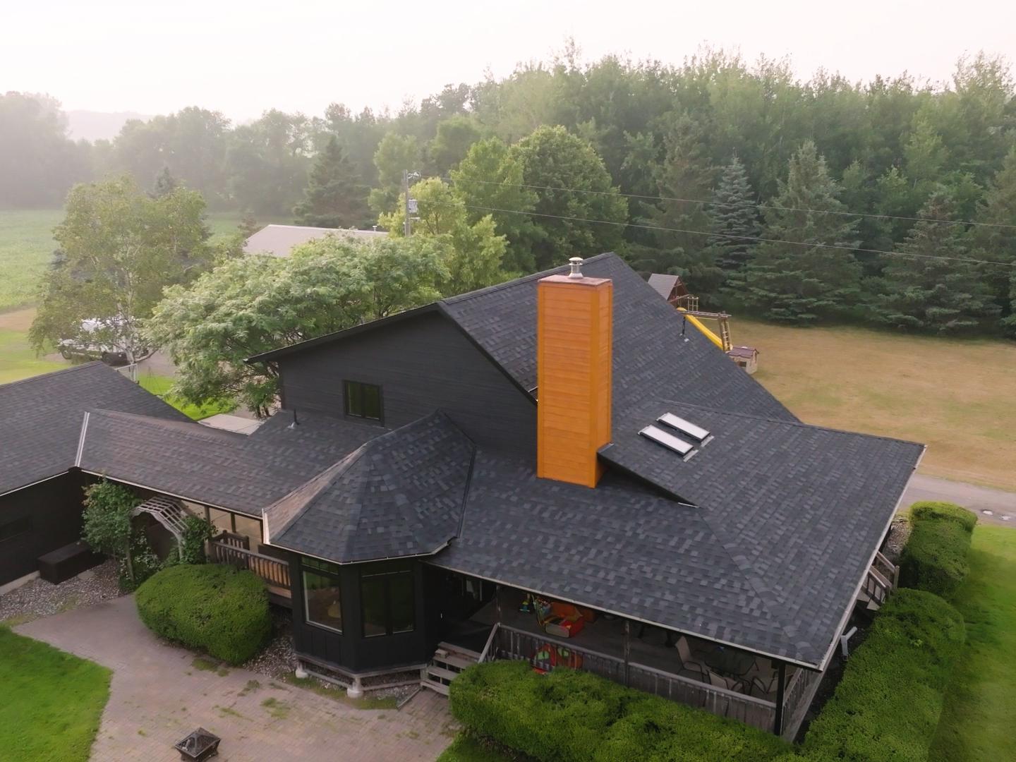 A contractor installing asphalt shingles and replacing siding on a residential roof. | Omega Exteriors