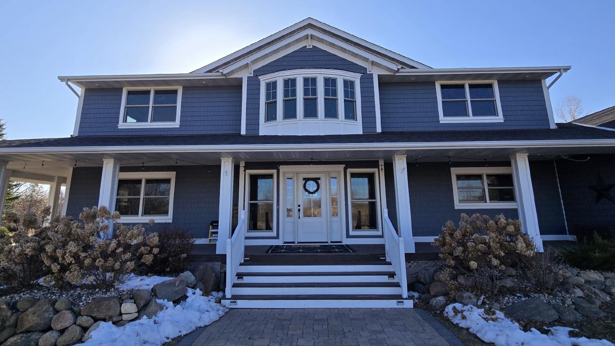 Blue two-story home with new white-trimmed windows and a front porch