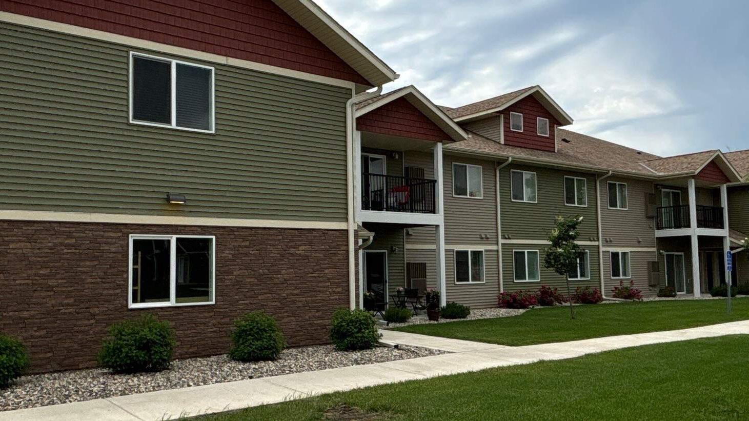 Apartment buildings with new windows above brick and green lap siding