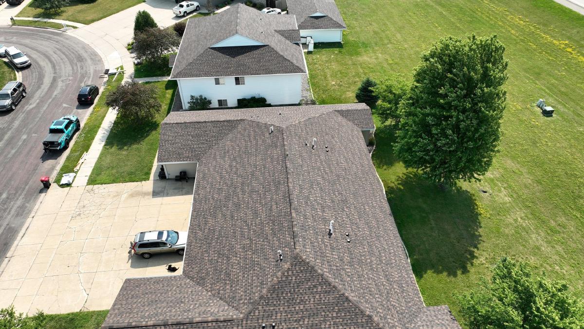 Aerial view of a restored asphalt shingle roof on a residential building