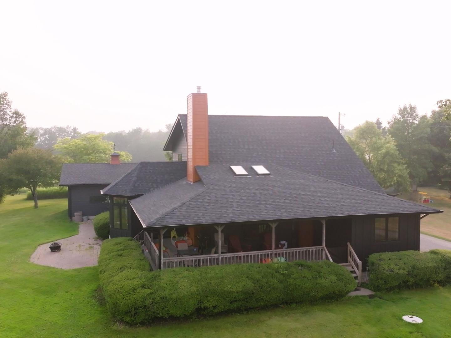A residential roof with asphalt shingles showing ongoing roof repair and siding installation. | Omega Exteriors