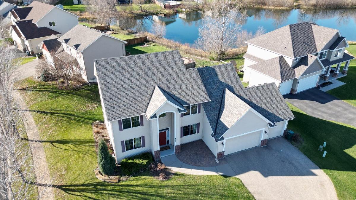 Aerial view of a replaced asphalt shingle roof on a two-story home by a pond