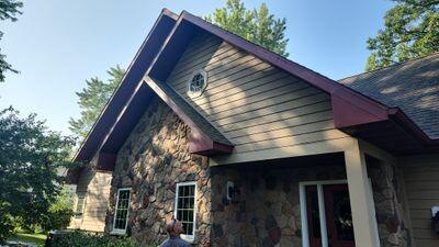 Tan lap siding with maroon trim on a stone-front home