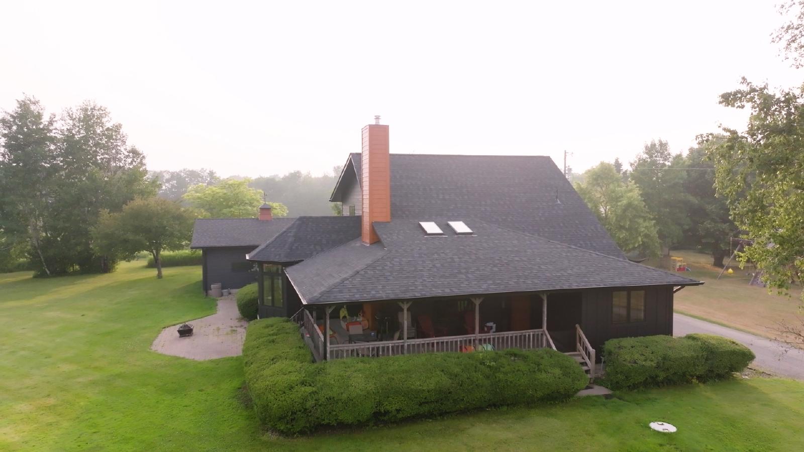 A residential roof with asphalt shingles showing ongoing roof repair and siding installation. | Omega Exteriors