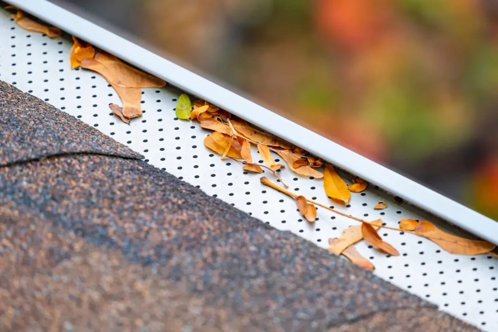 A professional installing gutter guards on a residential home for enhanced protection. | Omega Exteriors