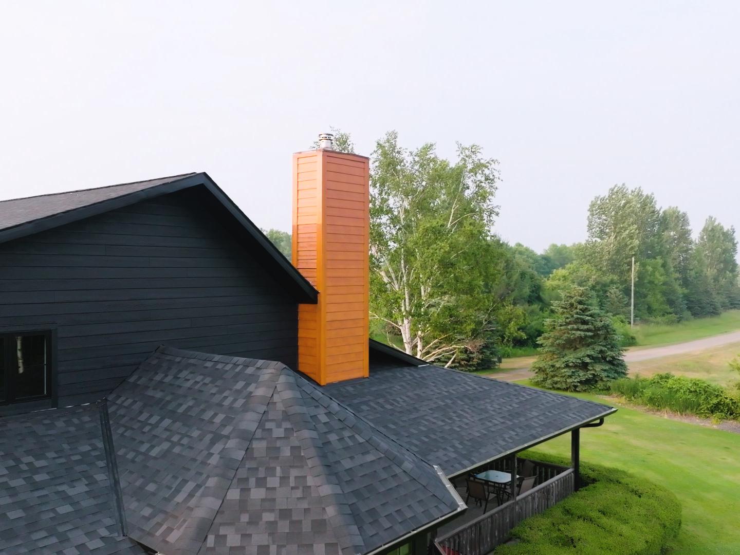 A contractor installing asphalt shingles on a residential roof with fiber cement siding. | Omega Exteriors