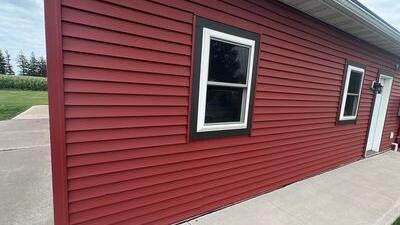 Red vinyl siding with dark-trimmed windows on a building
