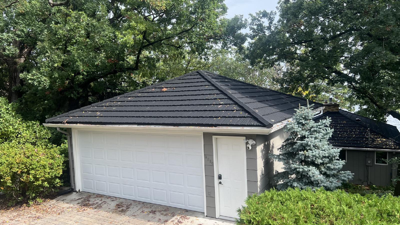 Metal roof installation on a residential home with new siding and seamless gutters. | Omega Exteriors