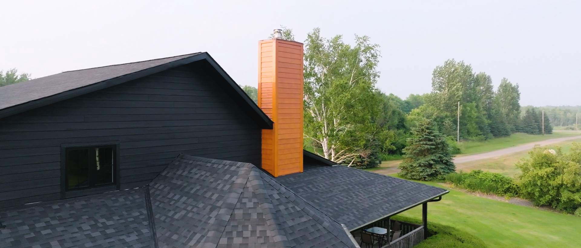 A contractor installing asphalt shingles on a residential roof with fiber cement siding. | Omega Exteriors