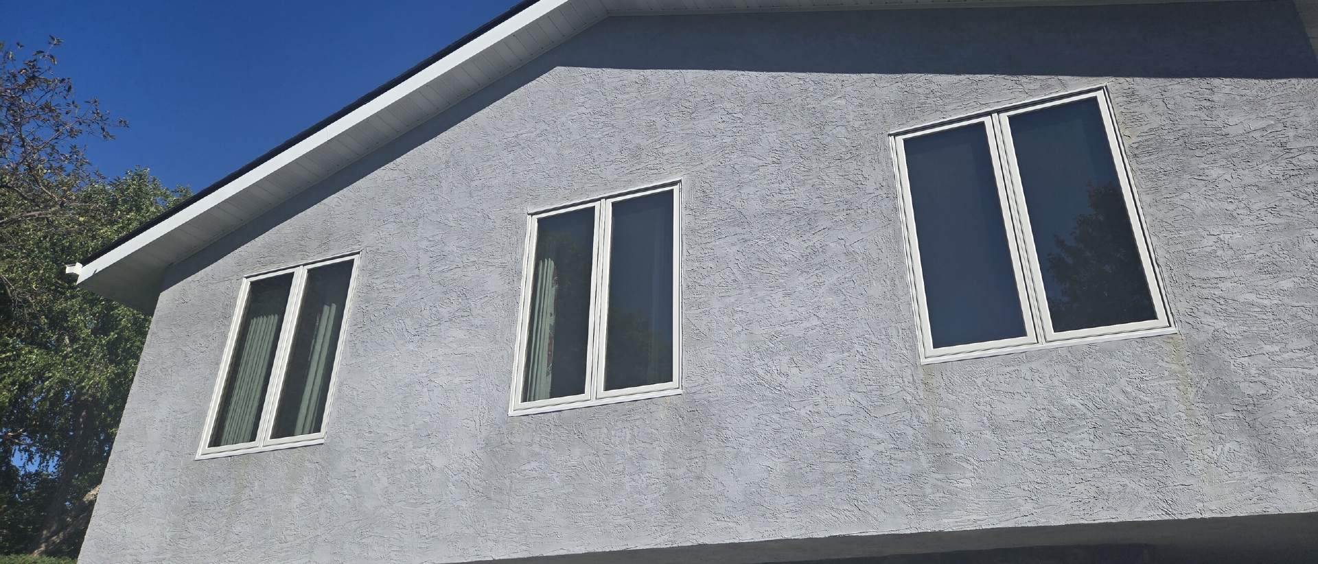 Replacement windows on a gray stucco home