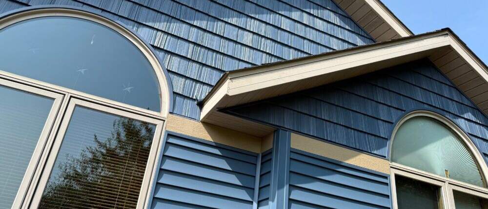 Blue shake siding on a home's gable above arched windows