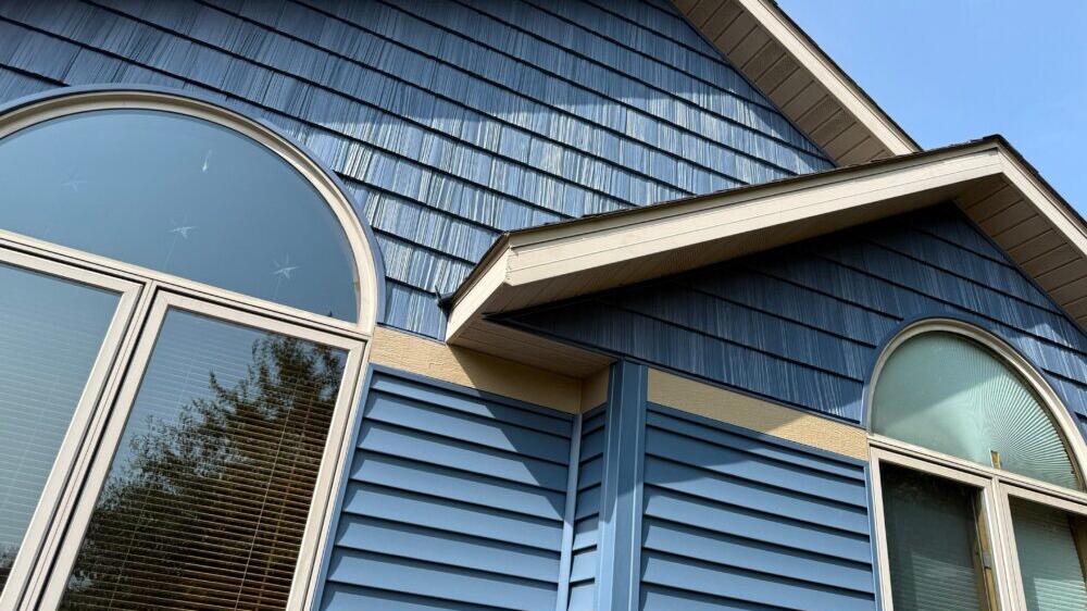 Blue shake siding on a home's gable above arched windows