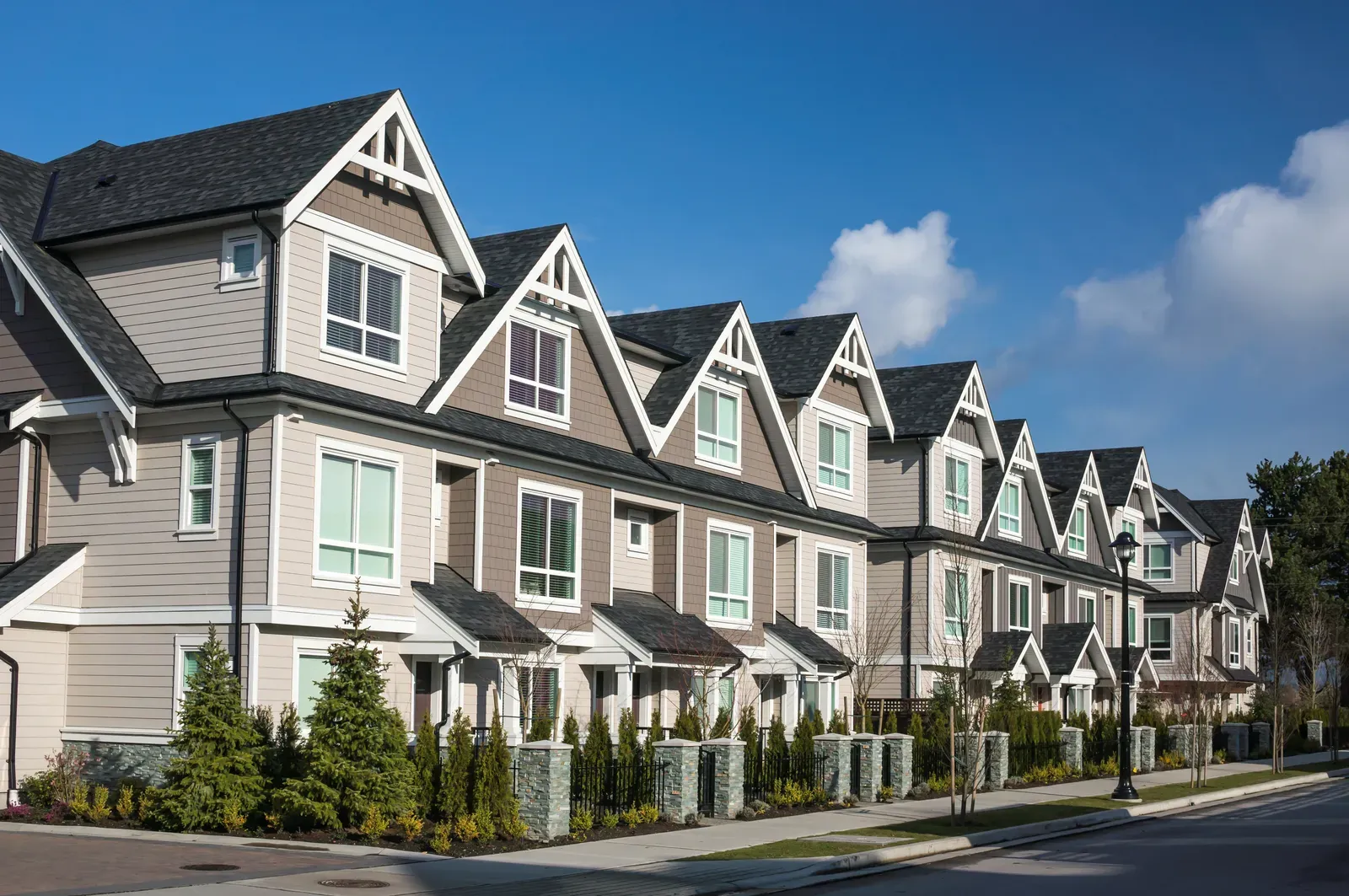 A multi-family home showing installation of asphalt roofing, vinyl siding, and aluminum gutters. | Omega Exteriors