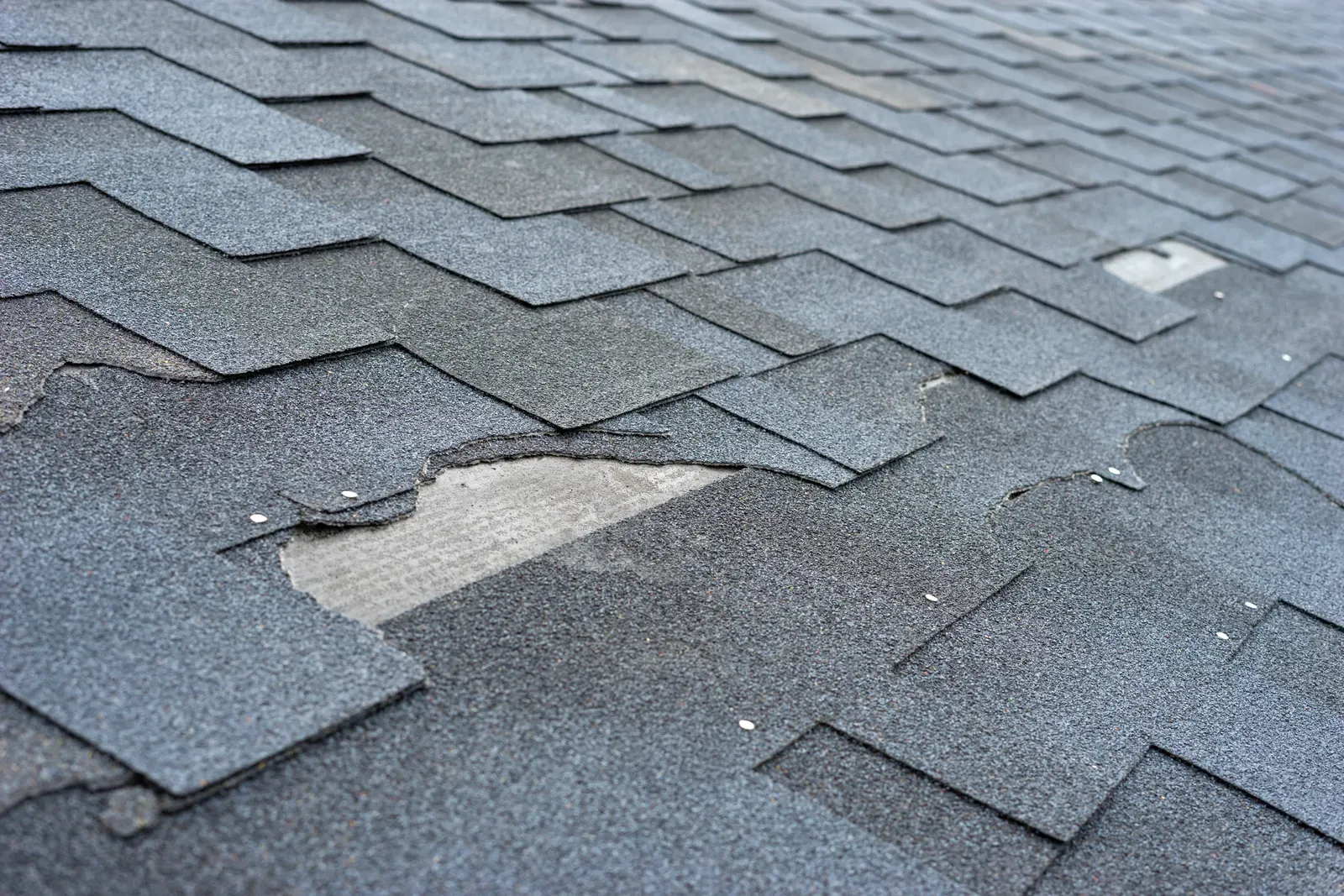 A residential roof repair in progress, showcasing asphalt shingles being replaced. | Omega Exteriors