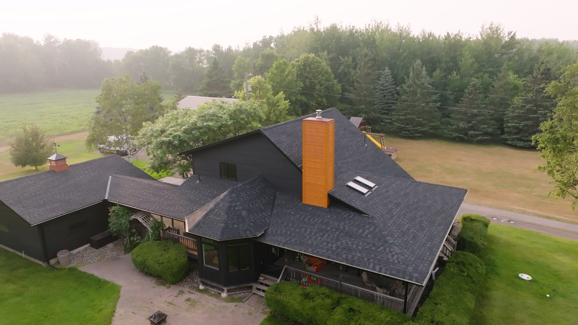 A contractor installing asphalt shingles and replacing siding on a residential roof. | Omega Exteriors