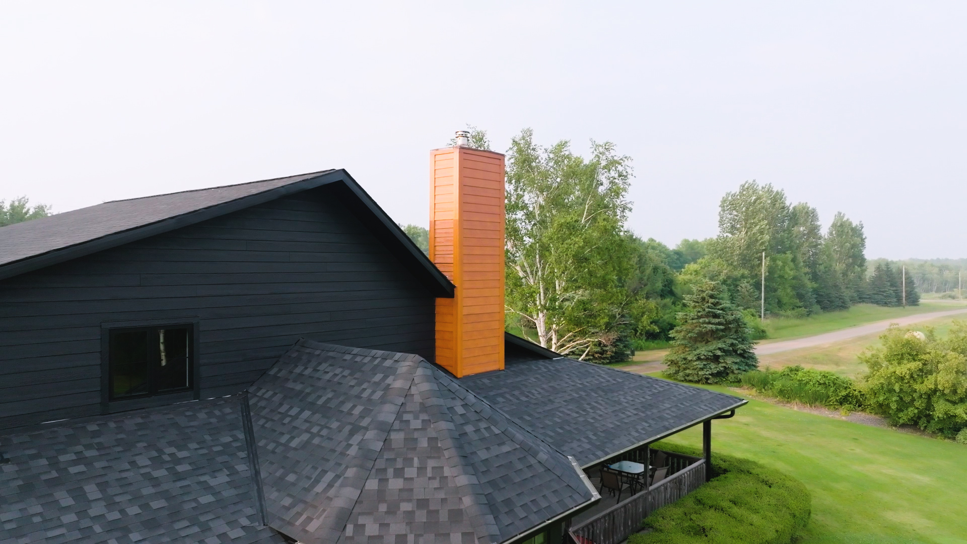 A contractor installing asphalt shingles on a residential roof with fiber cement siding. | Omega Exteriors